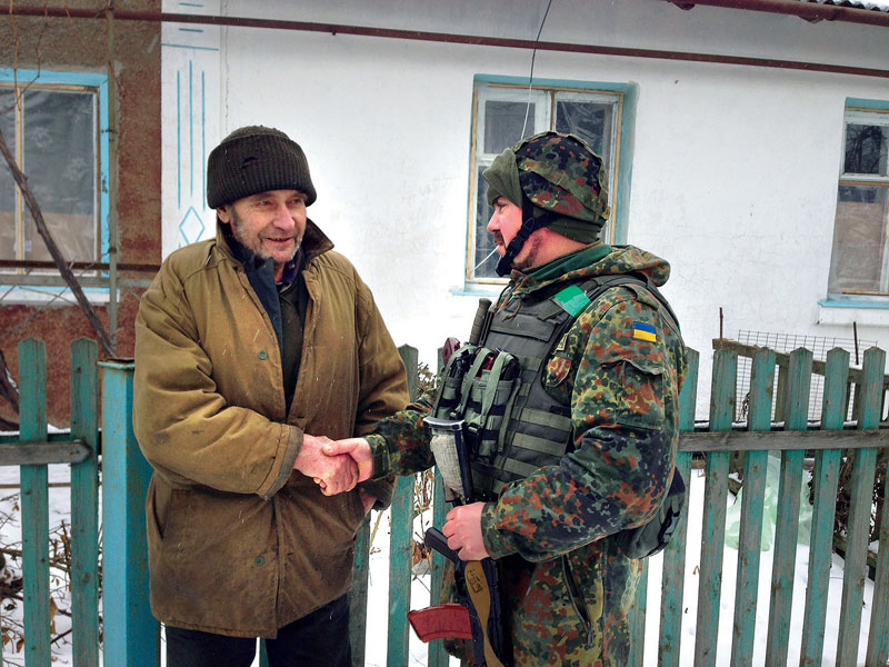 Oleksandr from the village of Opytne shakes hands with a Ukrainian officer.
