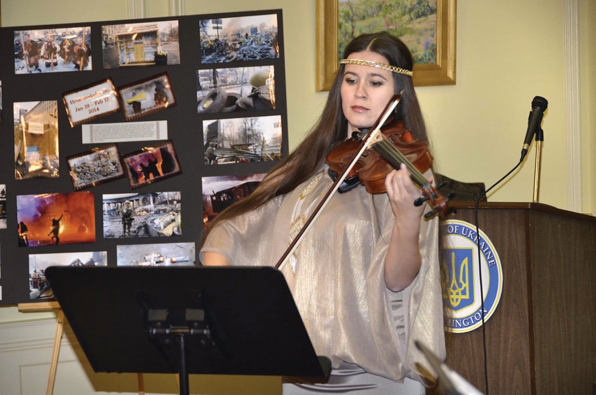 Violinist Solomia Gorokhivska of the Gerdan trio performs at the Embassy of Ukraine. In the background are photos from the Maidan.