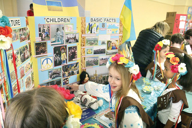Sophia Roof, 8, shows other Girl Scouts some of her favorite photos from the display the children helped make.