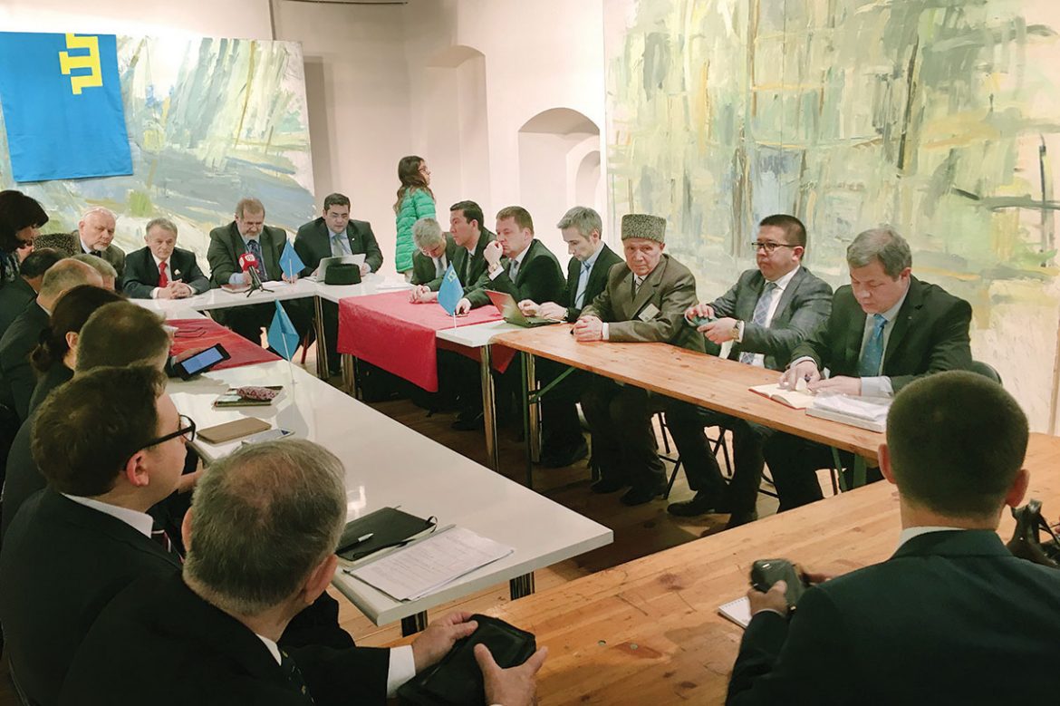 The executive committee of World Congress of Crimean Tatars commences its extraordinary coordinating meeting at the Arka Gallery in Vilnius, located in the historic Basilian Monastery complex of the Ukrainian Catholic Church of the Holy Trinity. Seated at the head table (from left) are: WCCT Vice-President Mükremin Şahin, Mustafa Dzhemilev, WCCT President Refat Chubarov, and WCCT Secretary General Namık Kemal Bayar.