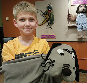 A young visitor enjoys one of the puppets on display as part of the exhibit “For Our Children.”