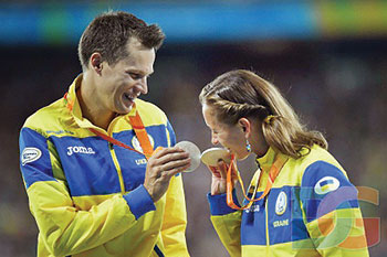 Silver medalists Iaroslav Denysenko (100-meter backstroke) and Viktoriia Savtsova (100-meter freestyle) celebrate their medals.