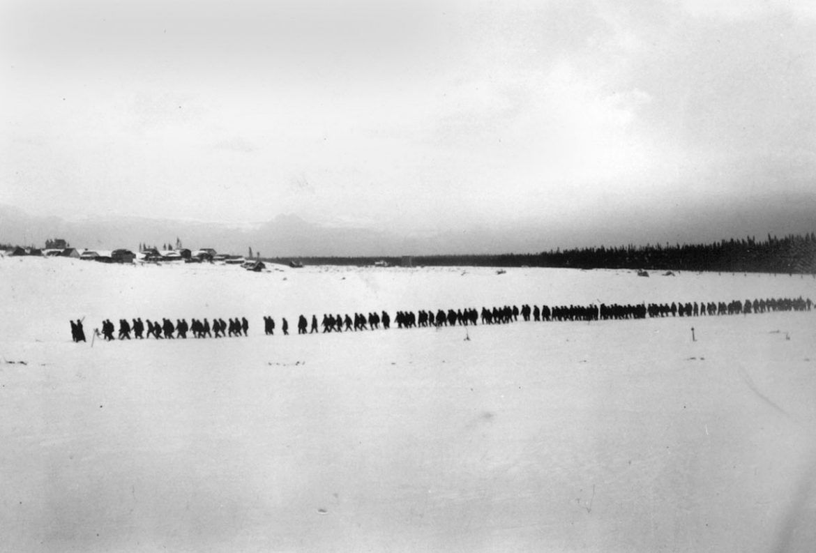 Internees cross Spirit Lake with the internment site in background, circa 1915.