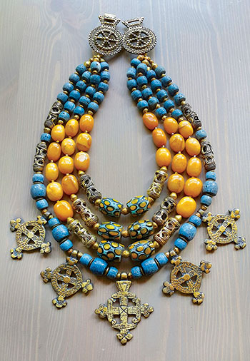 A necklace by Slava Salyuk, features yellow honey jade, Ghanaian Krobo beads, old Venetian trade beads, Ashanti brass beads, Coptic crosses, and brass Hutsul fibulas.