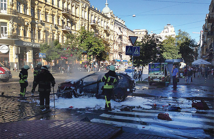 In this photograph taken by Olena Prytula before she realized her partner, Pavel Sheremet, was in the explosion on July 20, 2016, firefighters douse the vehicle in a Kyiv street.